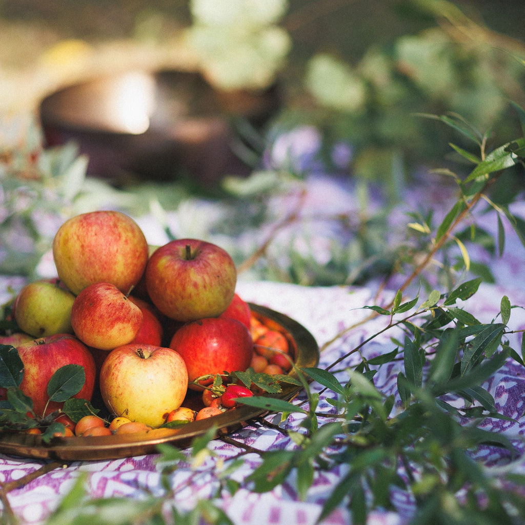 Apples on a plate with green leaves and a blurred natural background